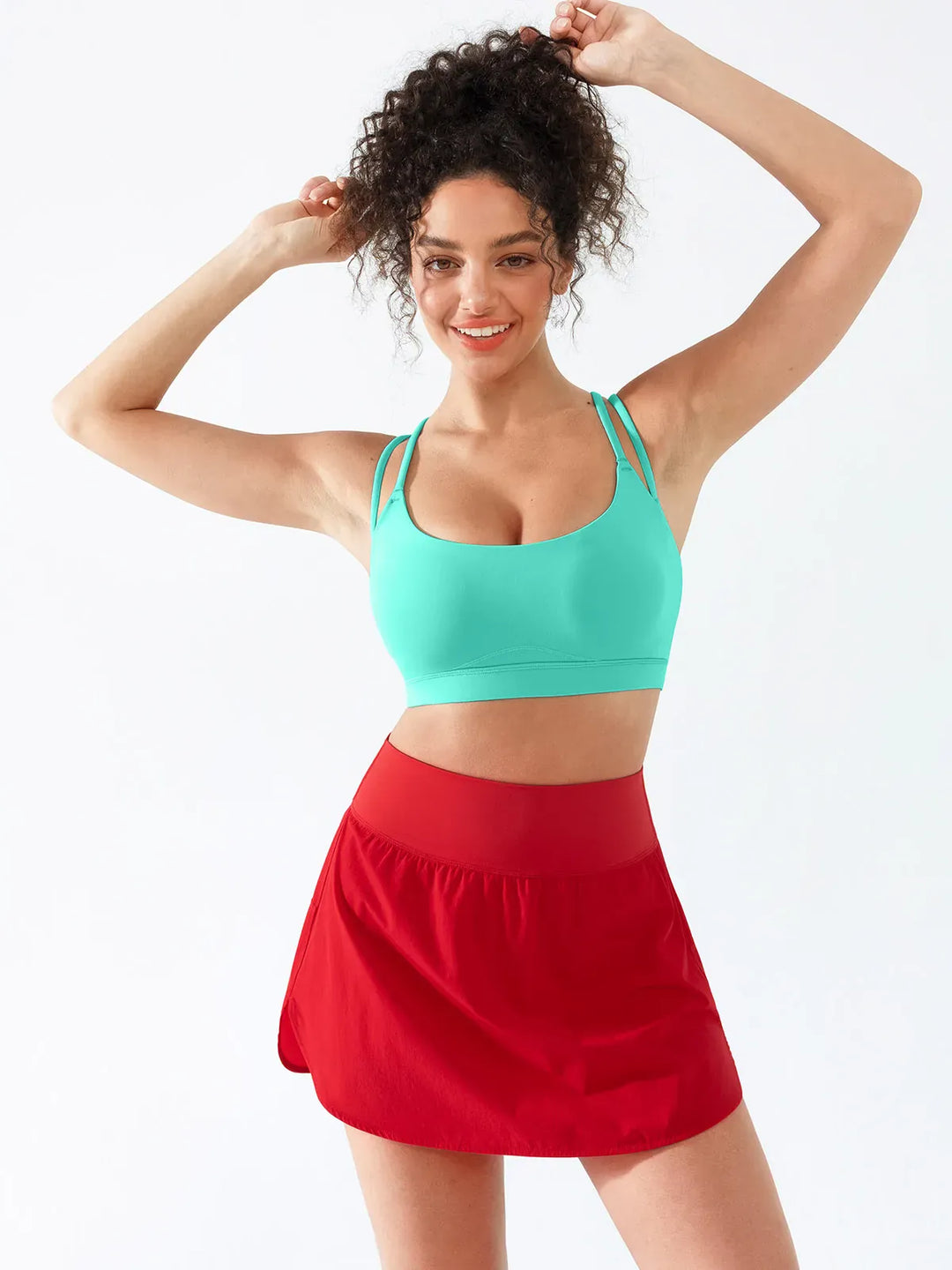 A model wearing a BRXL® Athletic High Waist Interior Pocket Tennis Skirt in