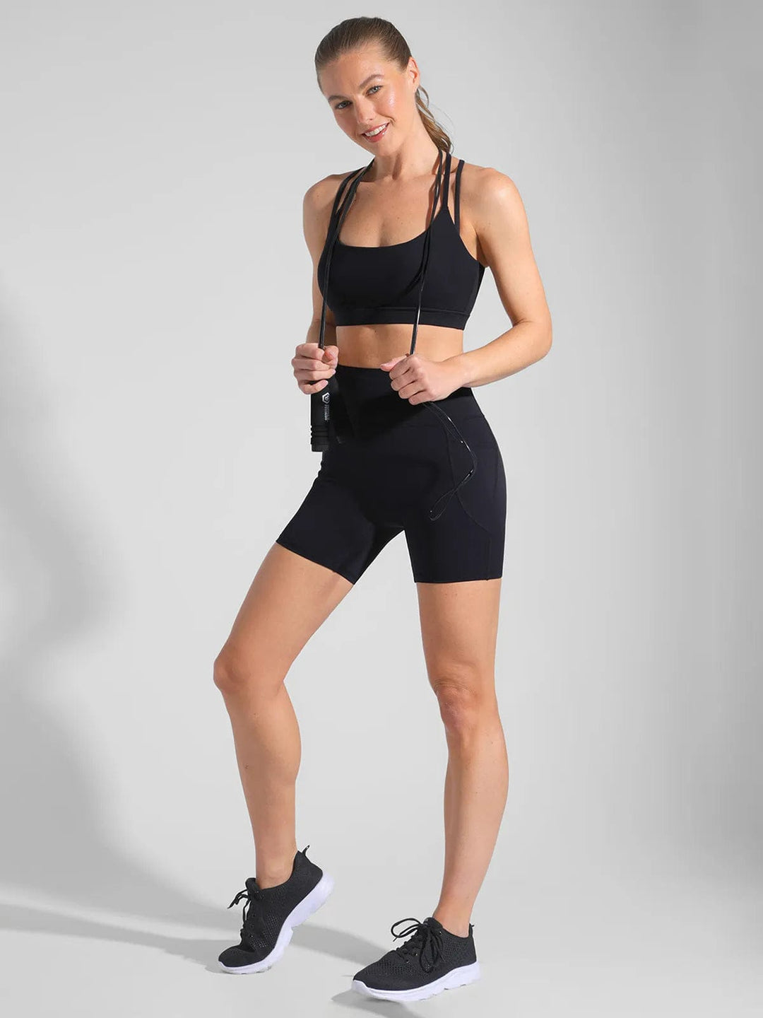 A model wearing a BRXL® Cross Strap Sports Bra High-Waisted Shorts Set in Set / Black / XS