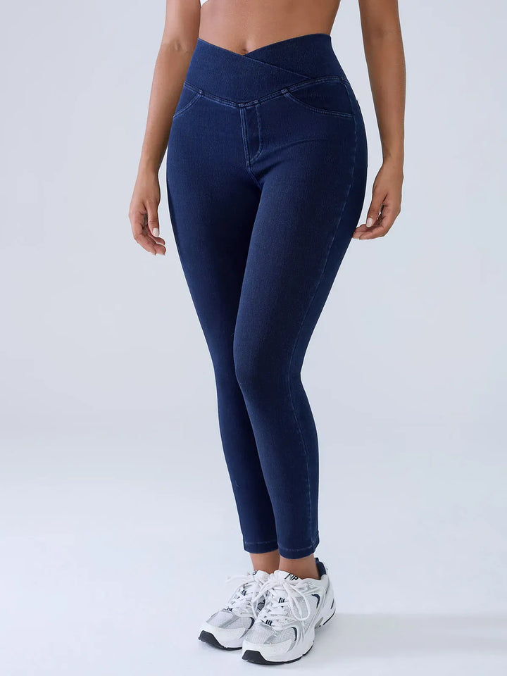 A model wearing a BRXL® Crossover Denim Sculpting Leggings with Pockets in