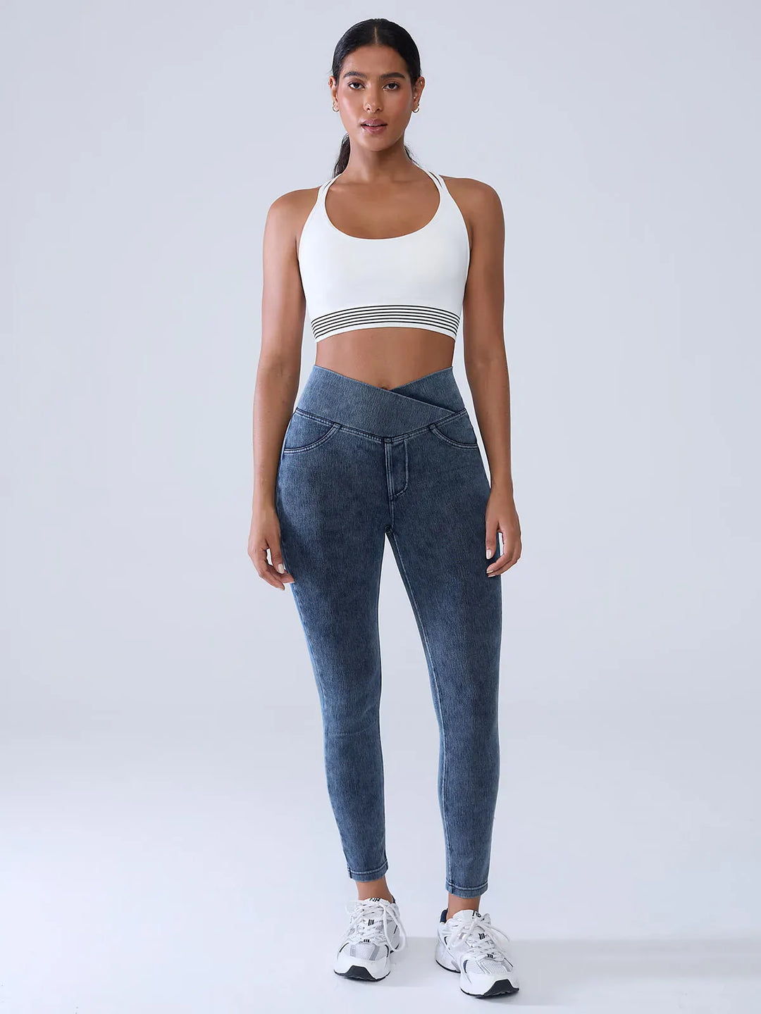 A model wearing a BRXL® Crossover Denim Sculpting Leggings with Pockets in