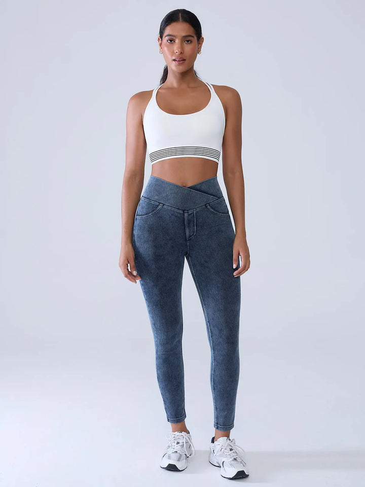 A model wearing a BRXL® Crossover Denim Sculpting Leggings with Pockets in
