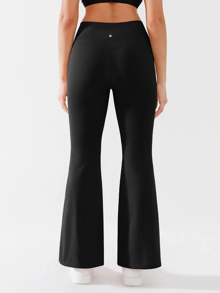 A model wearing a BRXL® Crossover Flared Yoga Pants in