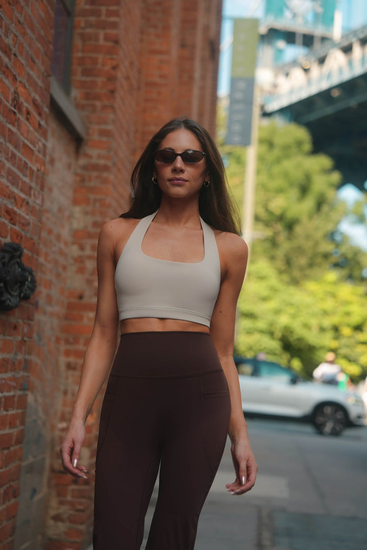 Woman in athletic wear standing against a brick wall with a cityscape background