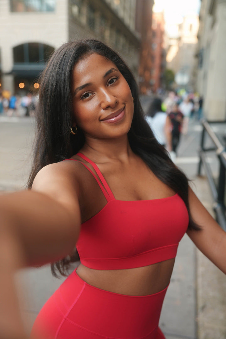 Woman in a red outfit taking a selfie on a city street
