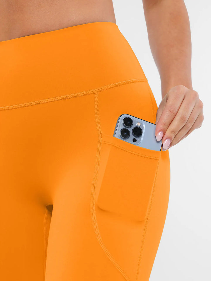 BRXL orange leggings with a pocket holding a phone.