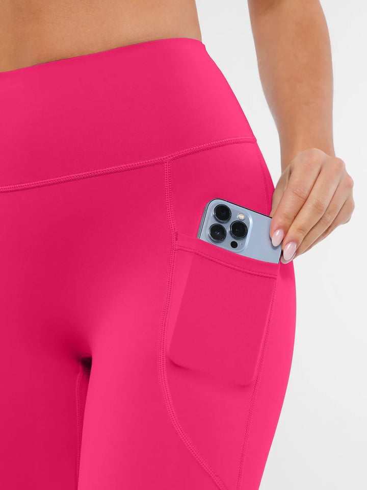 BRXL pink leggings with a pocket holding a phone.