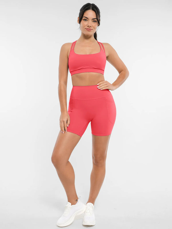 Woman wearing a coral biker shorts and sports bra.