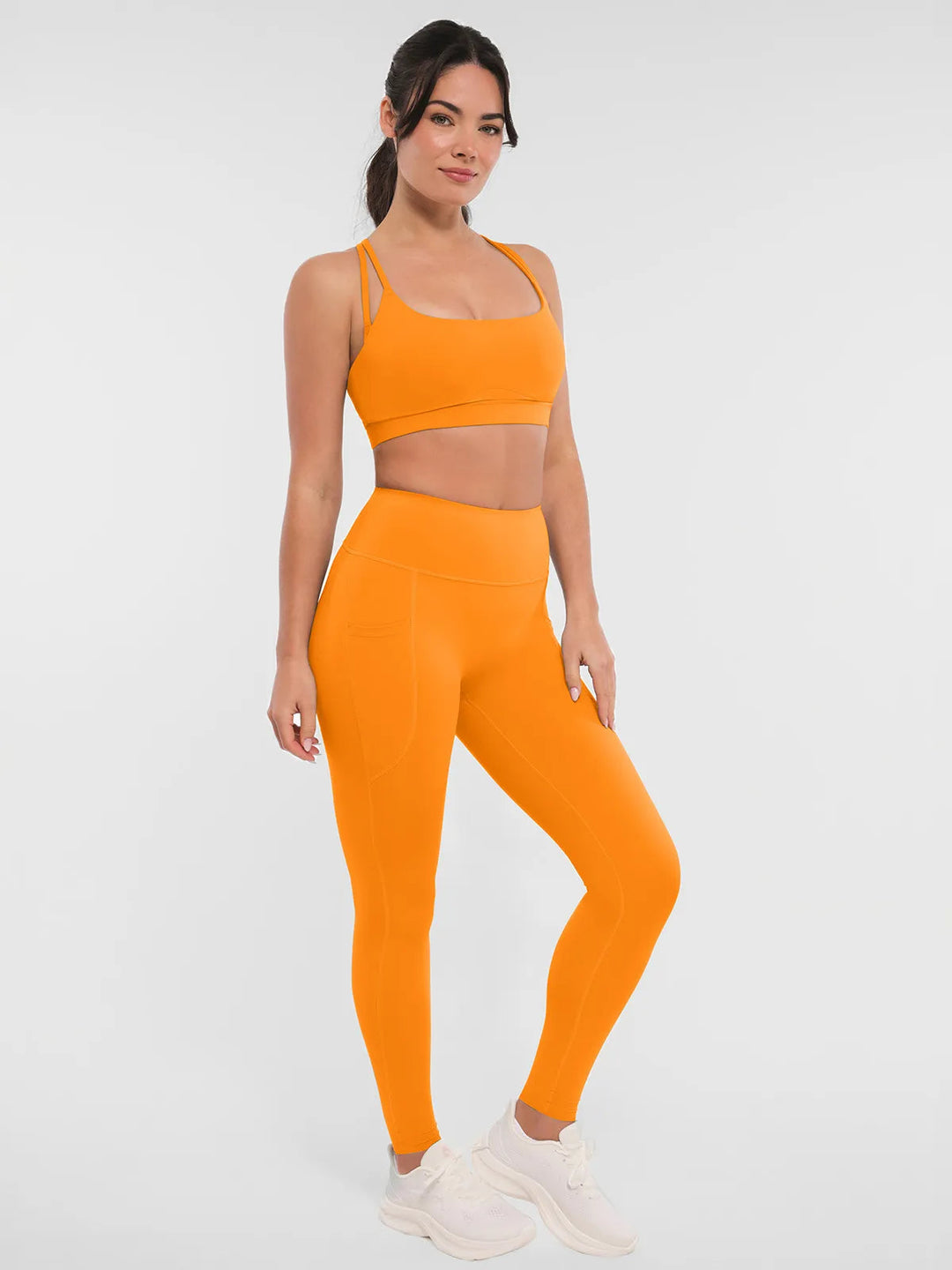 Woman wearing a BRXL orange leggings and sports bra.