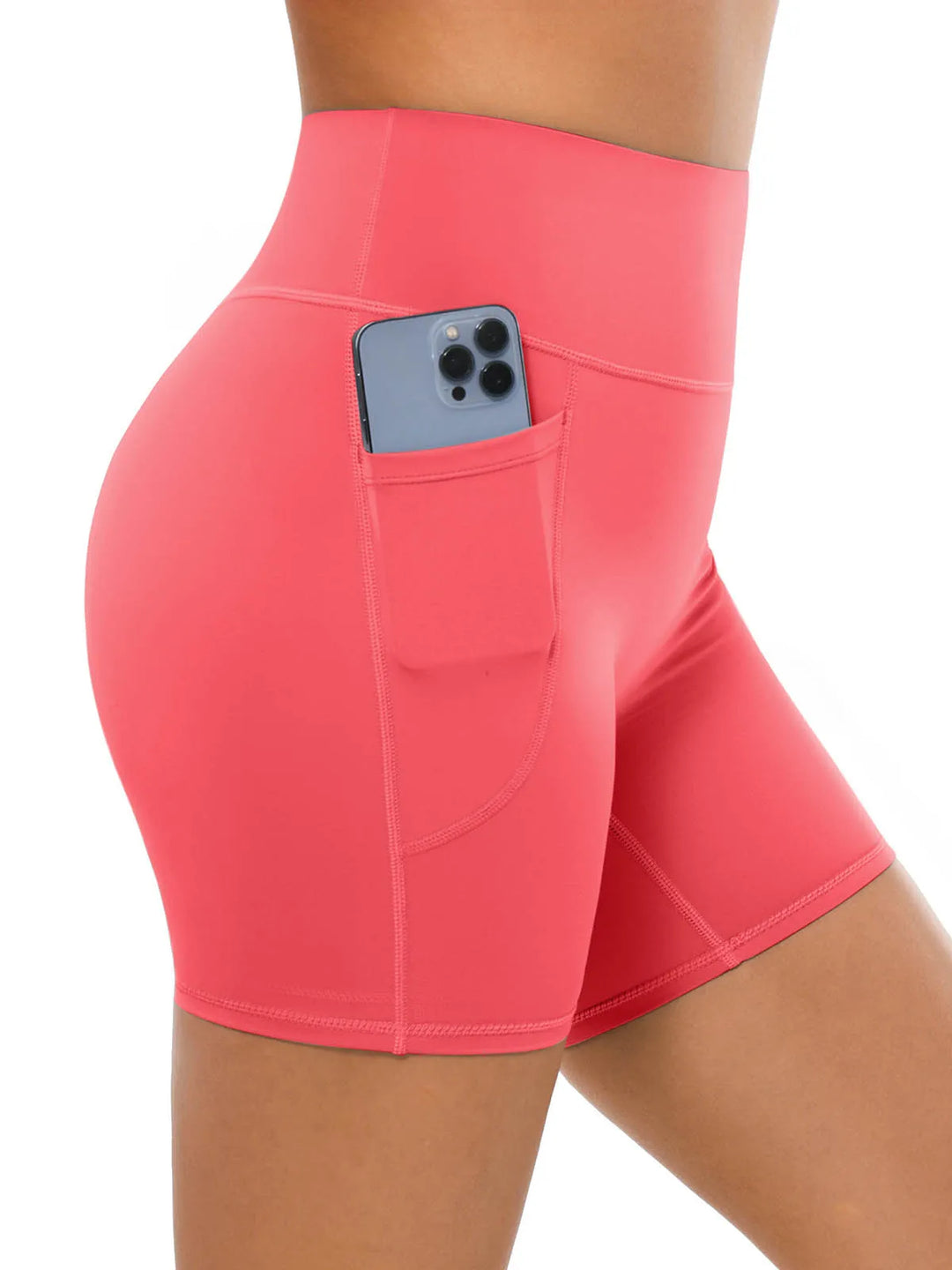 A model wearing high waisted coral biker shorts with a side pocket.