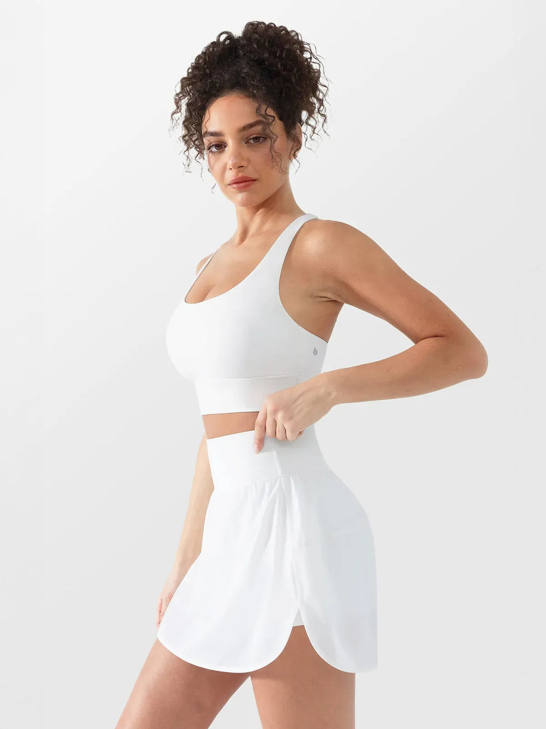 A model wearing a BRXL® Athletic High Waist Interior Pocket Tennis Skirt in