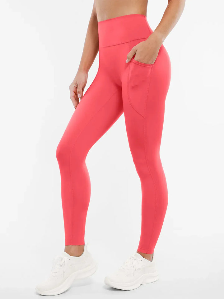 A model wearing a BRXL® BrxlZero™ High Rise Buttery Soft Yoga Leggings in Coral / XS