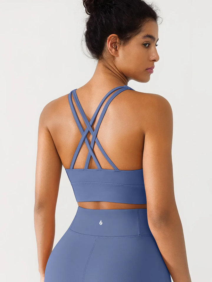 A model wearing a BRXL® Criss Cross Strappy Yoga Sports Bra in Blue / XS