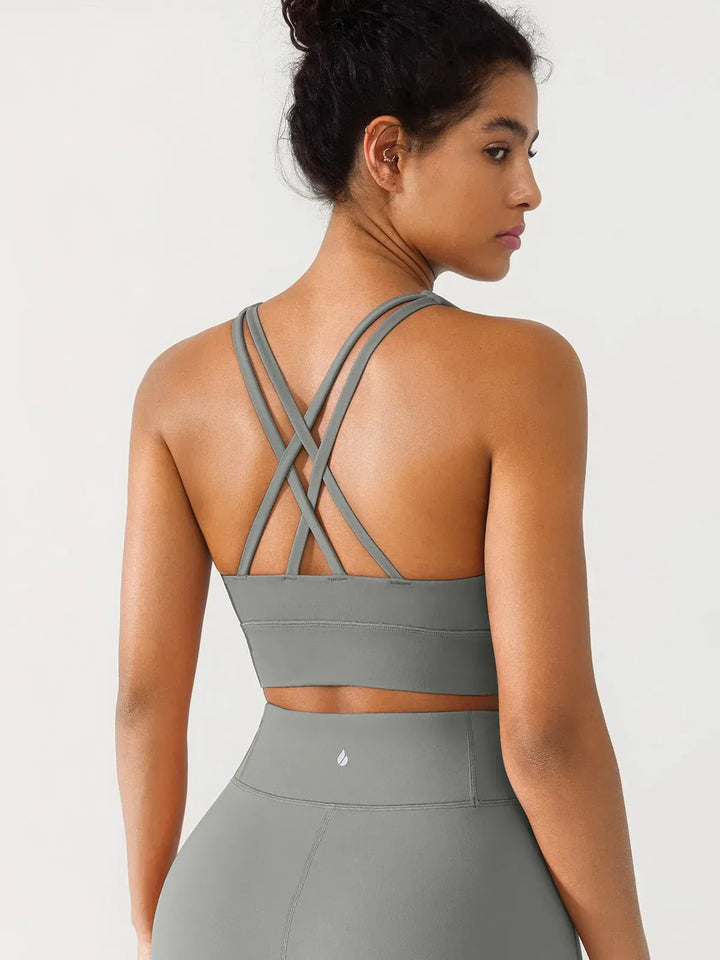 A model wearing a BRXL® Criss Cross Strappy Yoga Sports Bra in Gray / XS