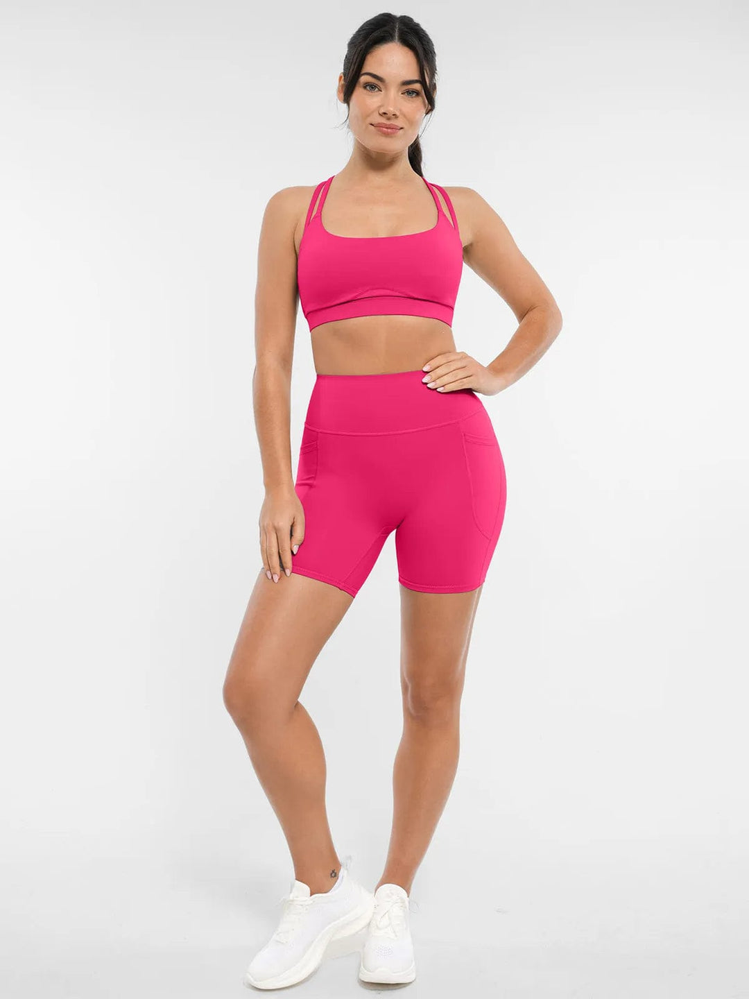 A model wearing a BRXL® Cross Strap Sports Bra High-Waisted Shorts Set in Set / Pink / XS