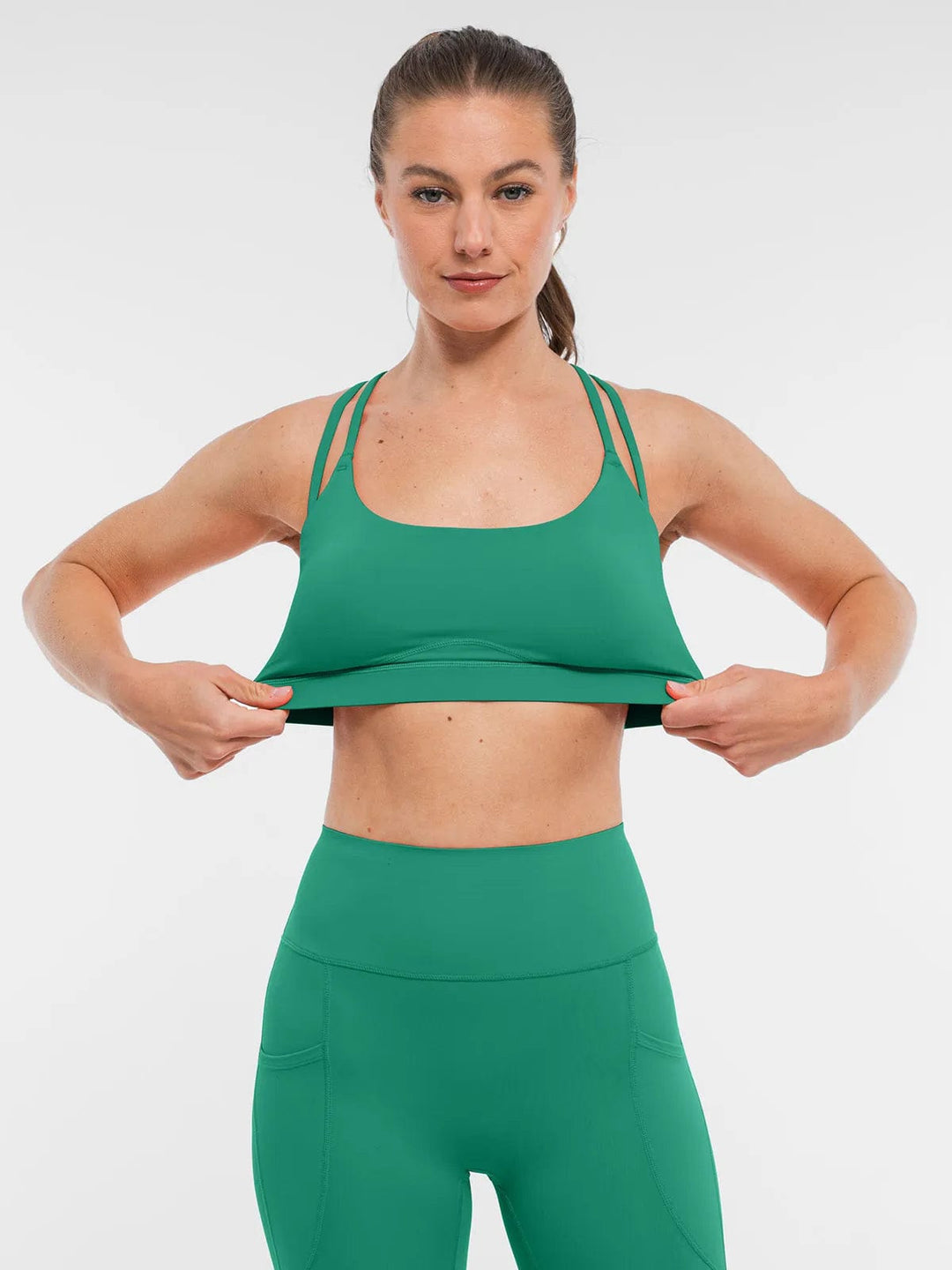 A model wearing a BRXL® Cross Strap Sports Bra Sculpted Leggings Set in