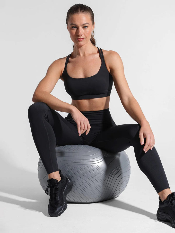 A model wearing a BRXL® Cross Strap Sports Bra Sculpted Leggings Set in