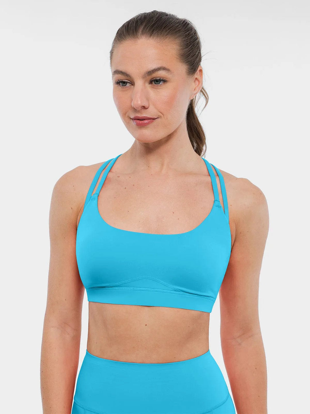 A model wearing a BRXL® Cross Strap Sports Bra Sculpted Leggings Set in Bra / Light Blue / XS