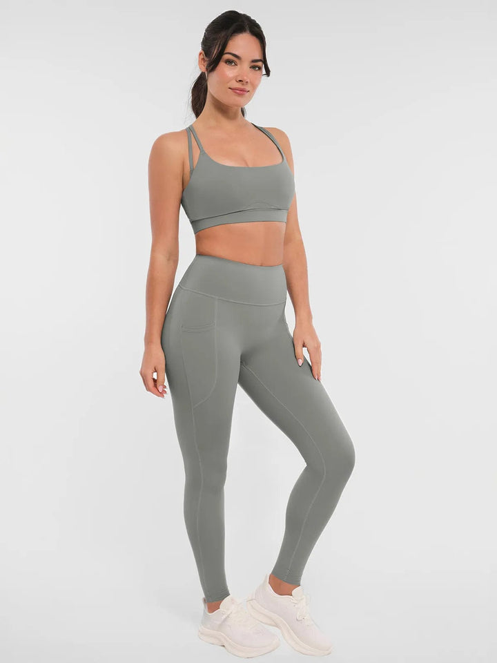 A model wearing a BRXL® Cross Strap Sports Bra Sculpted Leggings Set in Set / Gray / XS