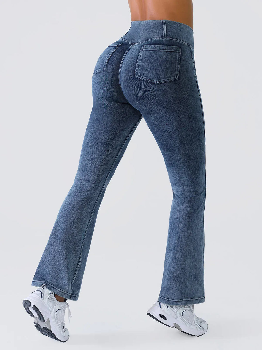 A model wearing a BRXL® Crossover Denim Flare Leggings with Pockets in Denim Blue / XS