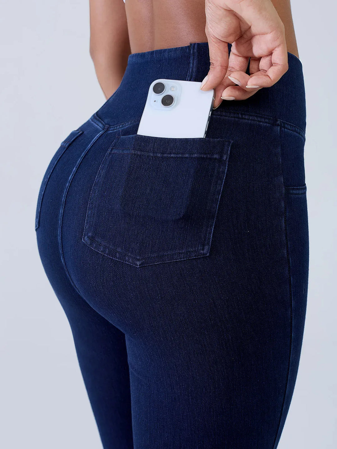 A model wearing a BRXL® Crossover Denim Sculpting Leggings with Pockets in