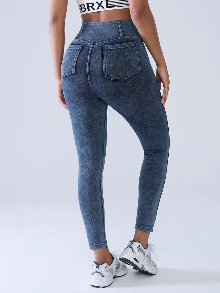 A model wearing a BRXL® Crossover Denim Sculpting Leggings with Pockets in