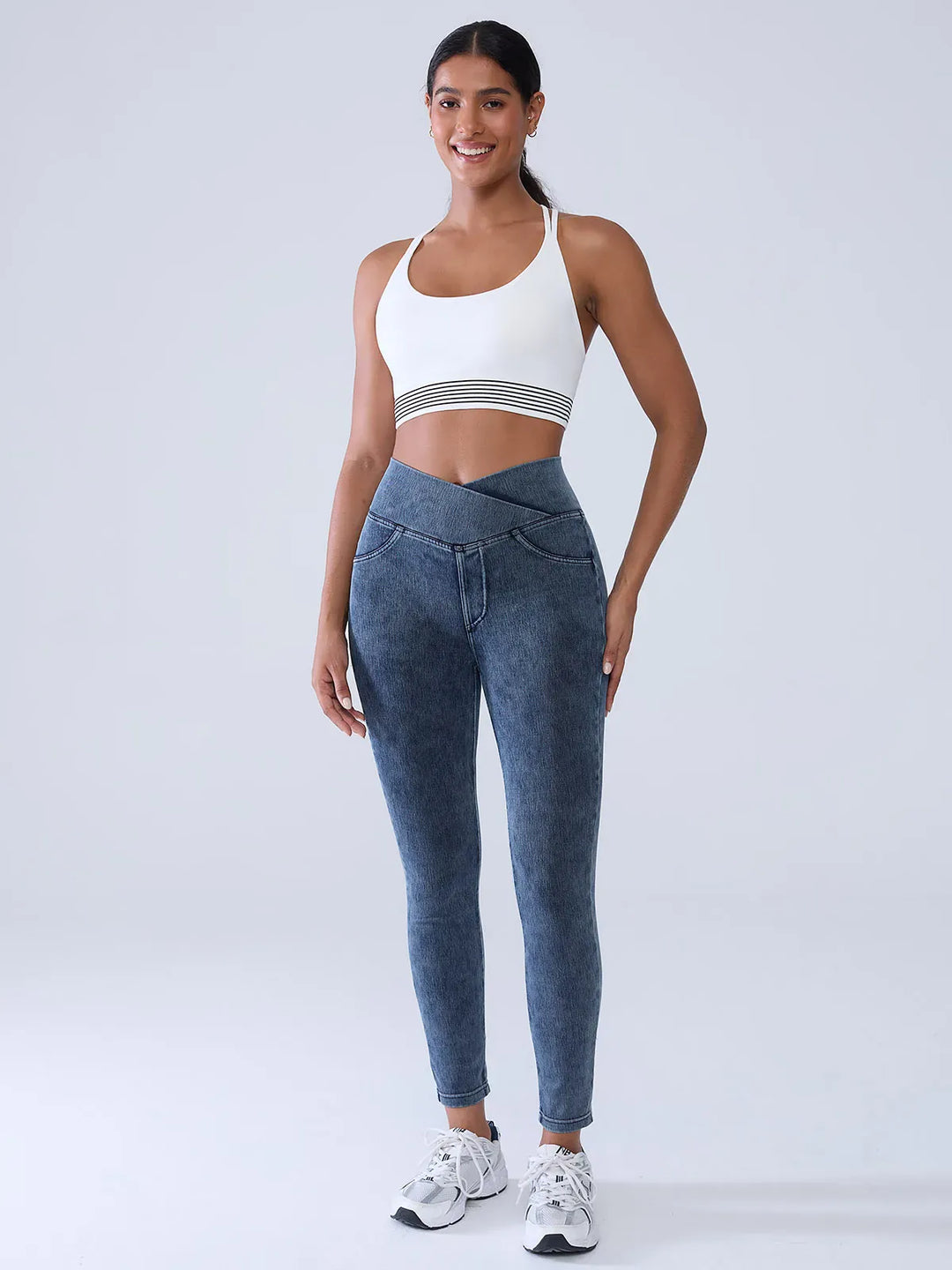 A model wearing a BRXL® Crossover Denim Sculpting Leggings with Pockets in