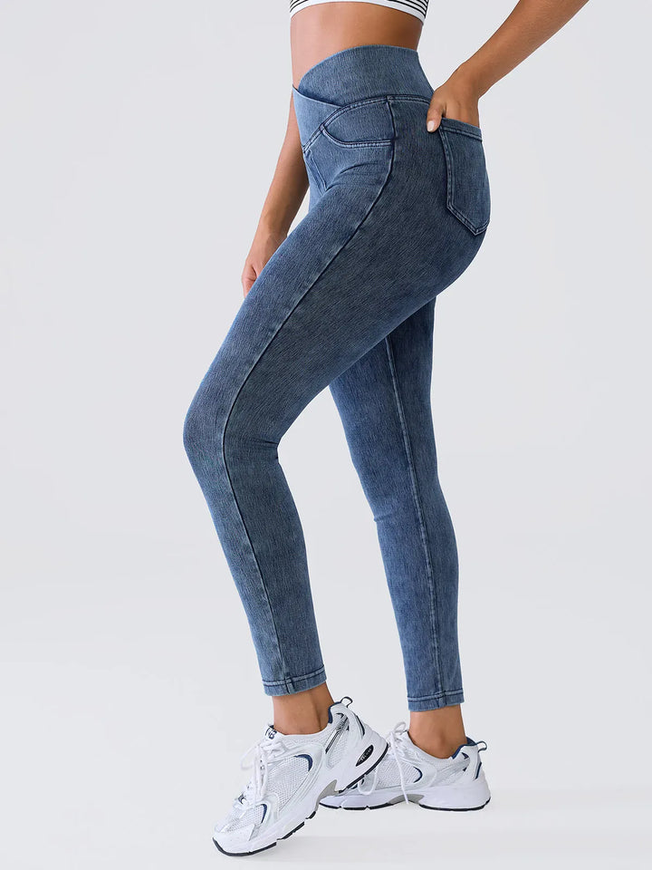 A model wearing a BRXL® Crossover Denim Sculpting Leggings with Pockets in Light Blue / XS