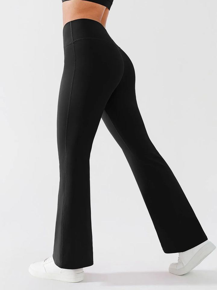 A model wearing a BRXL® Crossover Flared Yoga Pants in