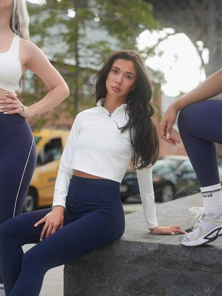 A model wearing a BRXL® Half Front Zipper Cropped Top Seamless Butt-Lifting Leggings Set in