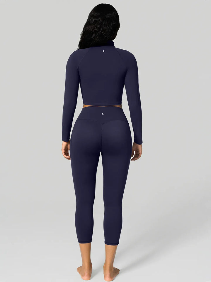 A model wearing a BRXL® Half Front Zipper Cropped Top Side Pockets Fleece Lined Leggings Set in