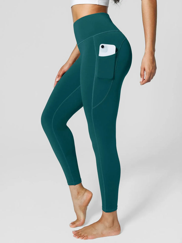 A model wearing a BRXL® High Rise Side Pockets Fleece Lined Leggings in Green / XS