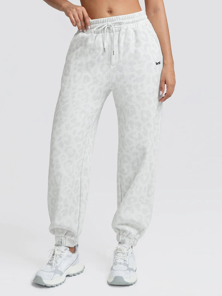 A model wearing a BRXL® Oversized Fleece Travel Jogger Sweatpants with Pockets White Leopard / XS