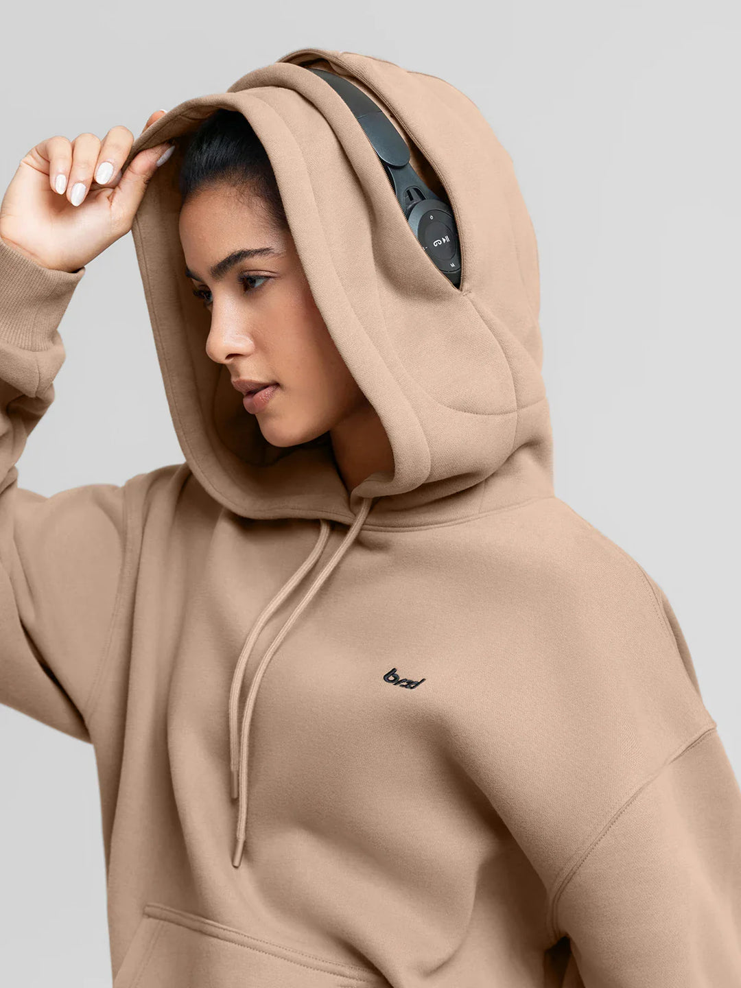 A model wearing a BRXL® Oversized Travel Pullover Hoodie with Headphone Slot