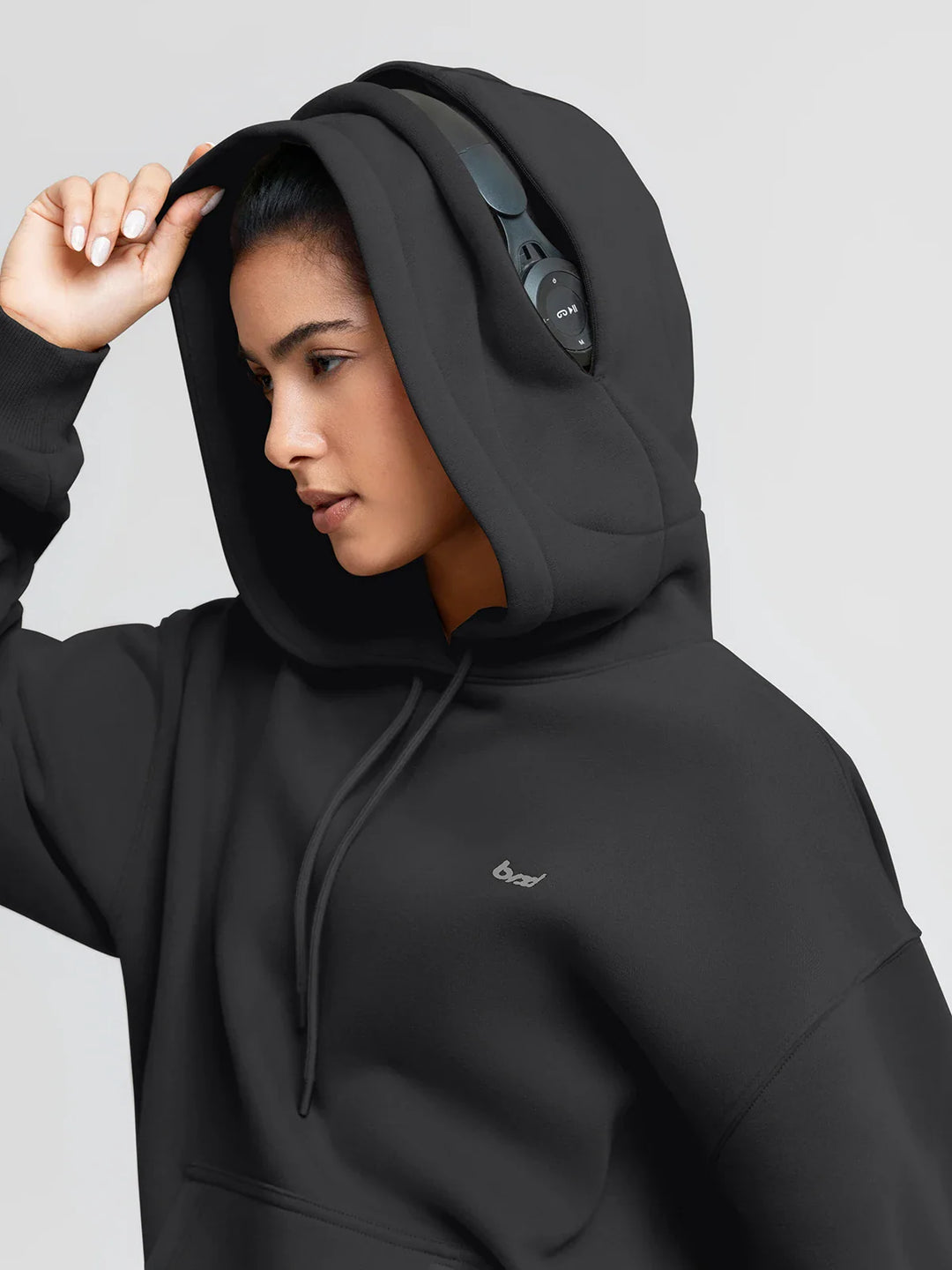 A model wearing a BRXL® Oversized Travel Pullover Hoodie with Headphone Slot