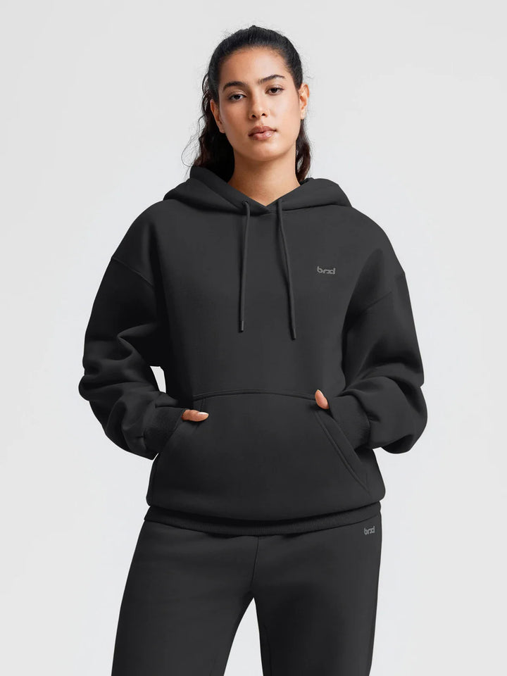 A model wearing a BRXL® Oversized Travel Pullover Hoodie with Headphone Slot Black / XS