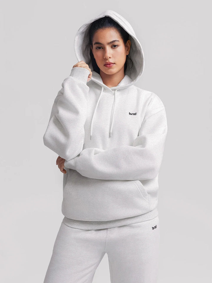 A model wearing a BRXL® Oversized Travel Pullover Hoodie with Headphone Slot Marble Grey / XS