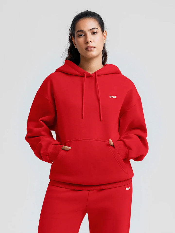 A model wearing a BRXL® Oversized Travel Pullover Hoodie with Headphone Slot Ruby Red / XS
