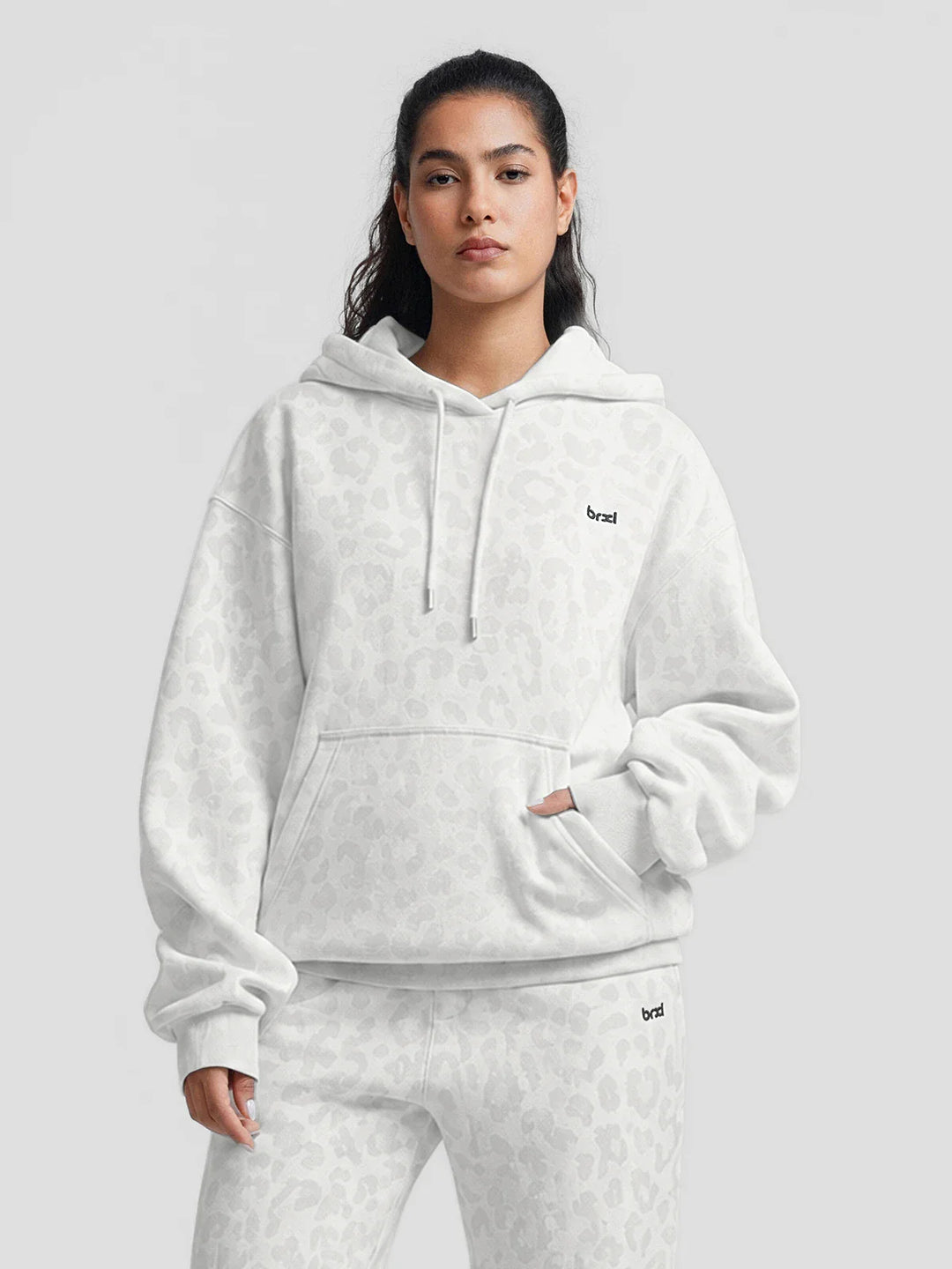 A model wearing a BRXL® Oversized Travel Pullover Hoodie with Headphone Slot White Leopard / XS