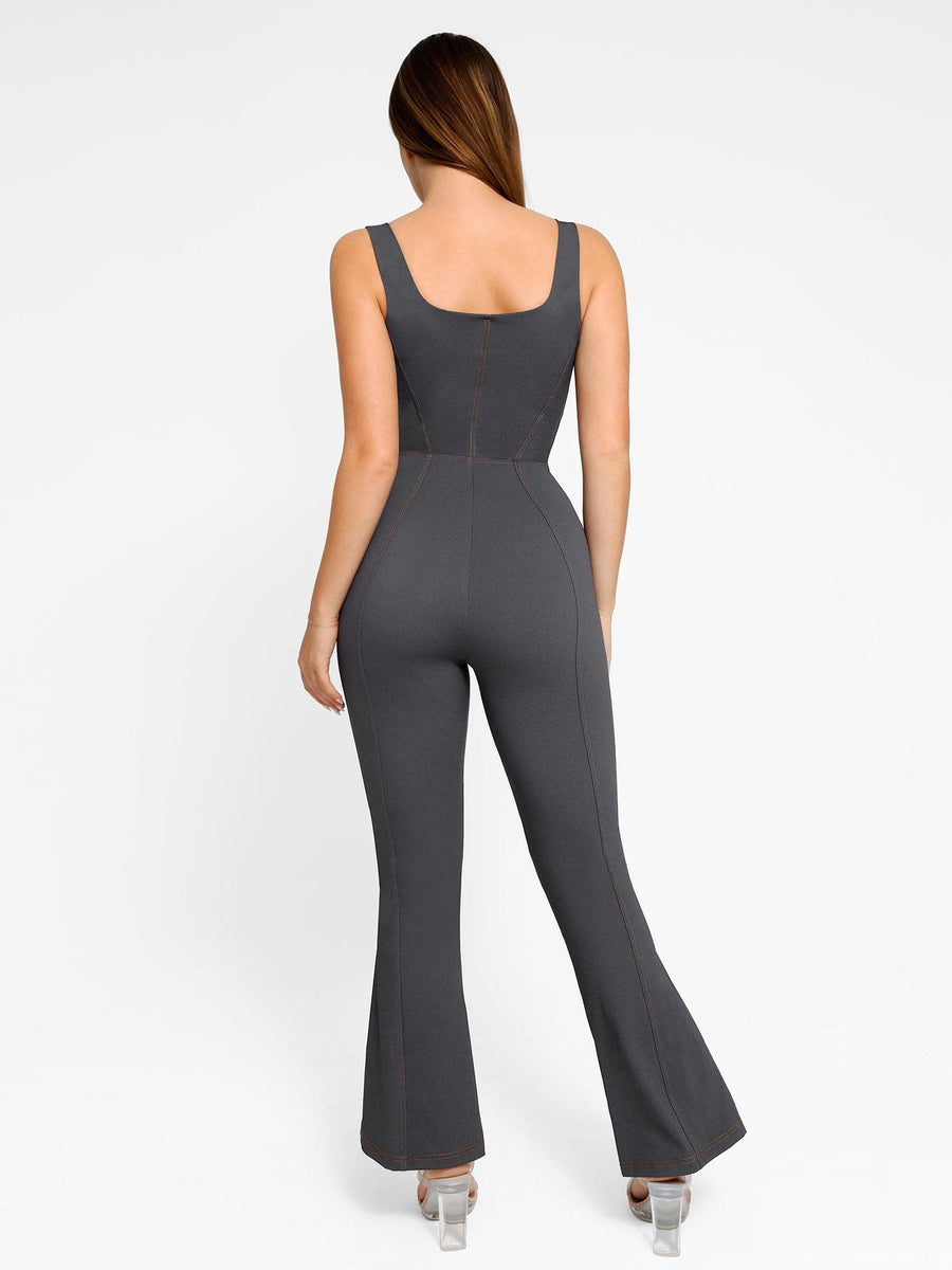 Back view of a woman wearing a charcoal grey denim square neck tank top flare leg jumpsuit with subtle contrast stitching.