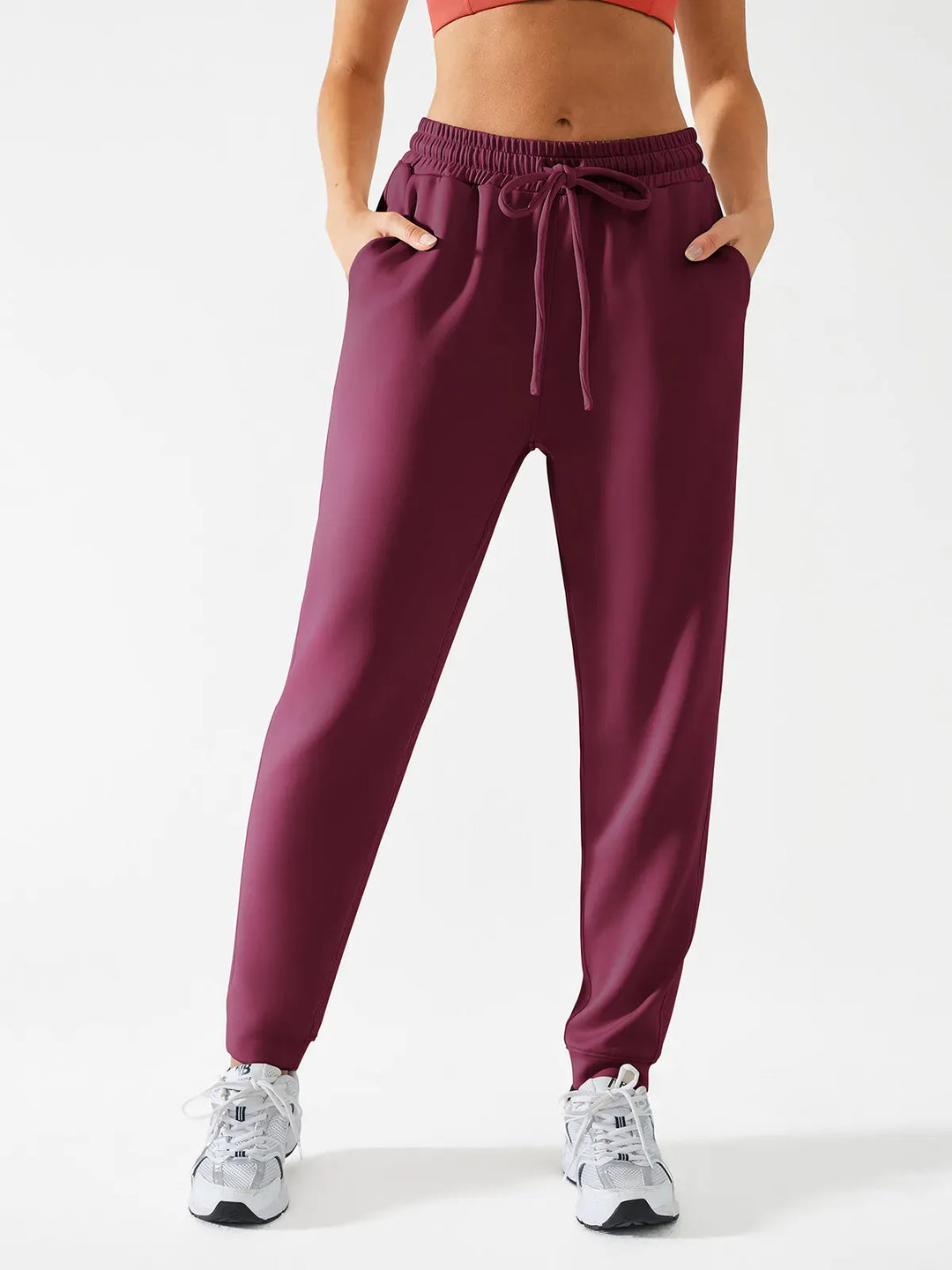 A model wearing a BRXL® Slim Fit Sweatpants with Pockets for Women in Red / XS